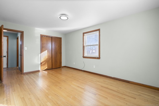 unfurnished bedroom featuring a closet, baseboards, and light wood finished floors