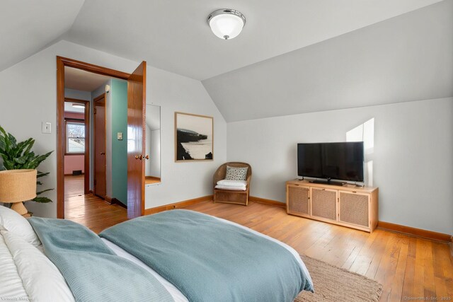 bedroom with lofted ceiling, baseboards, and hardwood / wood-style flooring