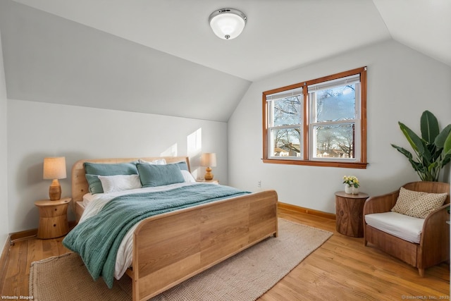 bedroom featuring light wood-type flooring, vaulted ceiling, and baseboards