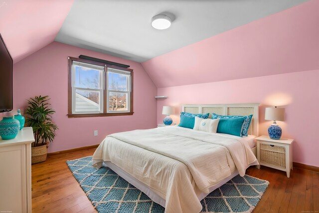 bedroom with lofted ceiling, wood-type flooring, and baseboards