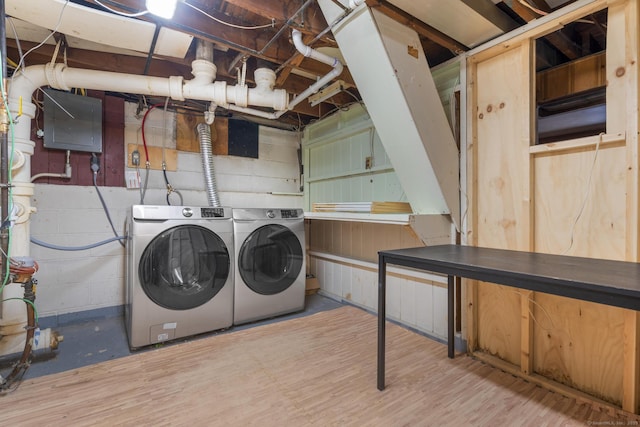 washroom featuring concrete block wall, laundry area, washer and clothes dryer, and wood finished floors