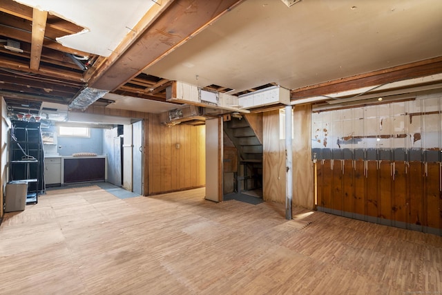 basement featuring wood walls, stairway, and wood finished floors