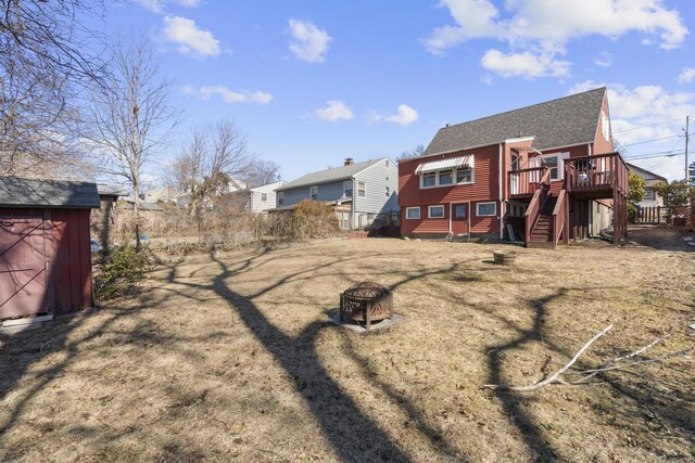 back of house featuring an outdoor fire pit, a shingled roof, a wooden deck, a shed, and an outdoor structure