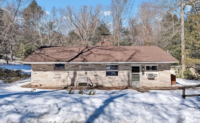 exterior space featuring a shingled roof, stone siding, and a chimney