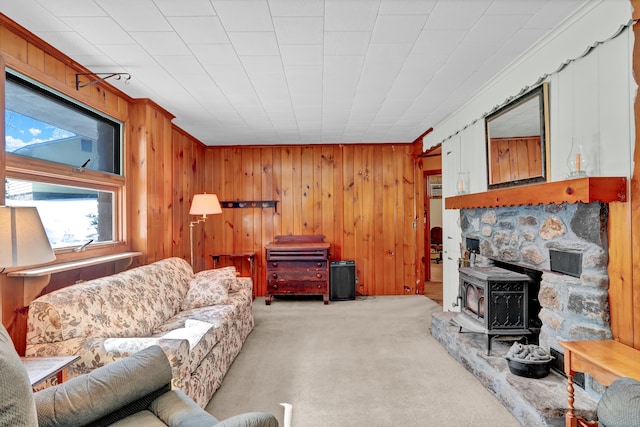 living area with a wood stove, wood walls, ornamental molding, and light colored carpet