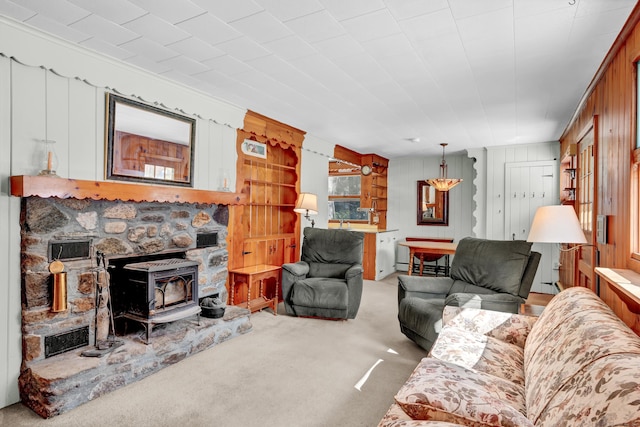 carpeted living area with a wood stove and wood walls