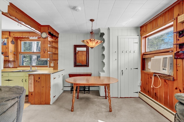 kitchen with a baseboard radiator, light colored carpet, a sink, light countertops, and decorative light fixtures