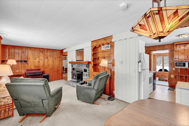 living room with a wood stove, wooden walls, and light colored carpet