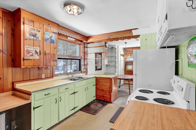 kitchen with range with electric stovetop, green cabinets, freestanding refrigerator, wood walls, and a sink