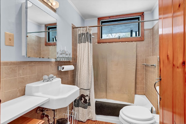 bathroom featuring toilet, a sink, tile walls, ornamental molding, and shower / bath combo