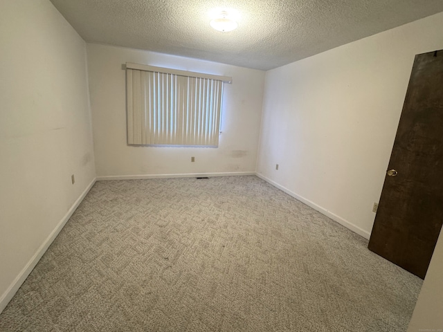 spare room featuring a textured ceiling, baseboards, and carpet flooring