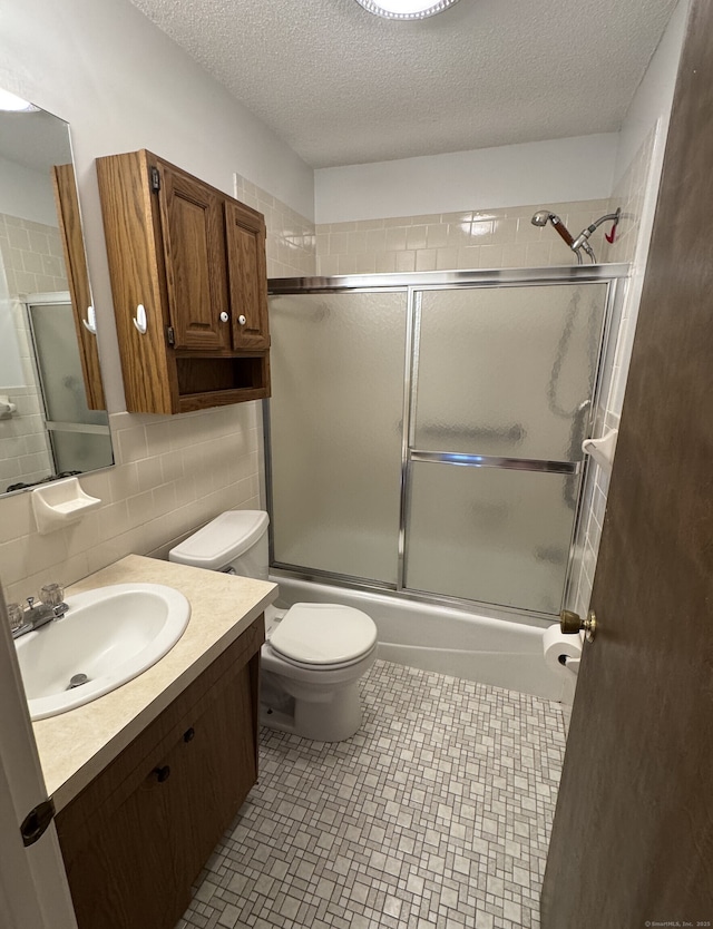 bathroom with decorative backsplash, a textured ceiling, toilet, and bath / shower combo with glass door