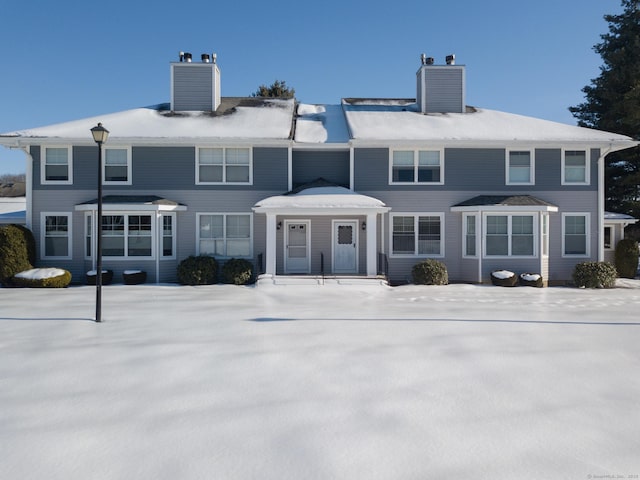 snow covered house with a chimney and cooling unit