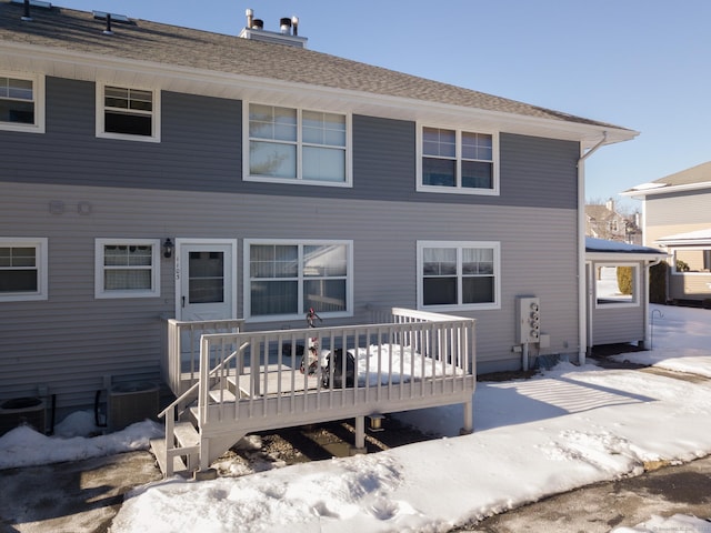 snow covered rear of property with central air condition unit and a wooden deck