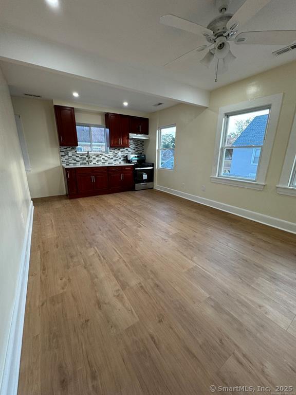 kitchen with reddish brown cabinets, tasteful backsplash, light countertops, visible vents, and light wood-type flooring