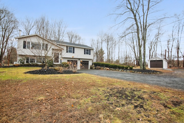 raised ranch featuring aphalt driveway, an outbuilding, a front lawn, and a garage