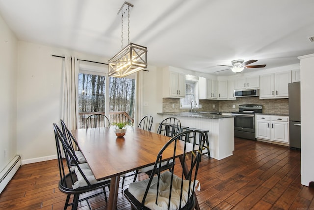 dining area featuring a baseboard radiator, ceiling fan with notable chandelier, visible vents, baseboards, and dark wood finished floors