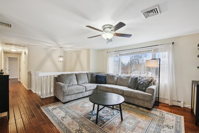 living area with attic access, a baseboard radiator, visible vents, and dark wood finished floors