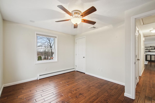 unfurnished room featuring dark wood-type flooring, a baseboard radiator, visible vents, and baseboards