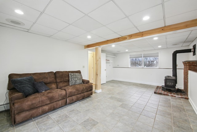 tiled living room featuring recessed lighting, a drop ceiling, a wood stove, and baseboards