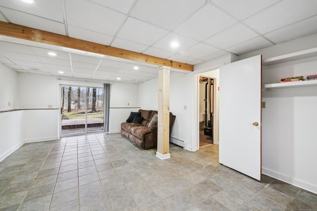 basement featuring baseboard heating, a drop ceiling, and baseboards