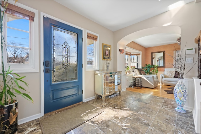 foyer featuring a wealth of natural light, arched walkways, and baseboards