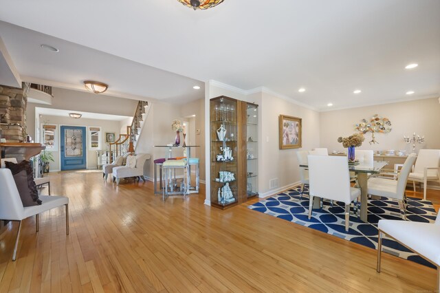 dining room with baseboards, light wood-style flooring, ornamental molding, stairs, and recessed lighting