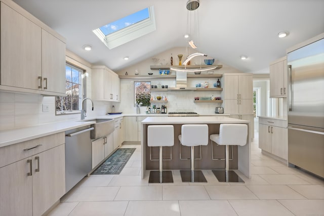 kitchen with a breakfast bar, stainless steel appliances, light brown cabinetry, a sink, and wall chimney range hood