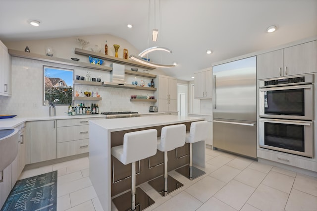 kitchen with light tile patterned floors, lofted ceiling, a breakfast bar area, stainless steel appliances, and light countertops