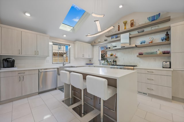 kitchen with a breakfast bar area, light tile patterned floors, light countertops, stainless steel dishwasher, and wall chimney range hood