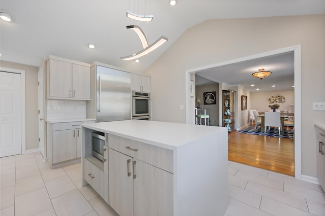 kitchen with light tile patterned floors, lofted ceiling, light countertops, appliances with stainless steel finishes, and a kitchen island