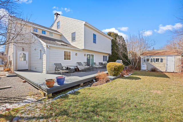 rear view of property featuring an outbuilding, roof with shingles, a yard, a chimney, and a wooden deck