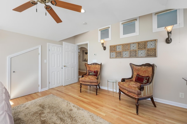 sitting room with arched walkways, wood finished floors, a ceiling fan, and baseboards