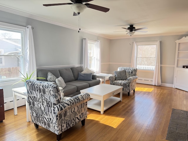 living room with hardwood / wood-style flooring, baseboard heating, and crown molding