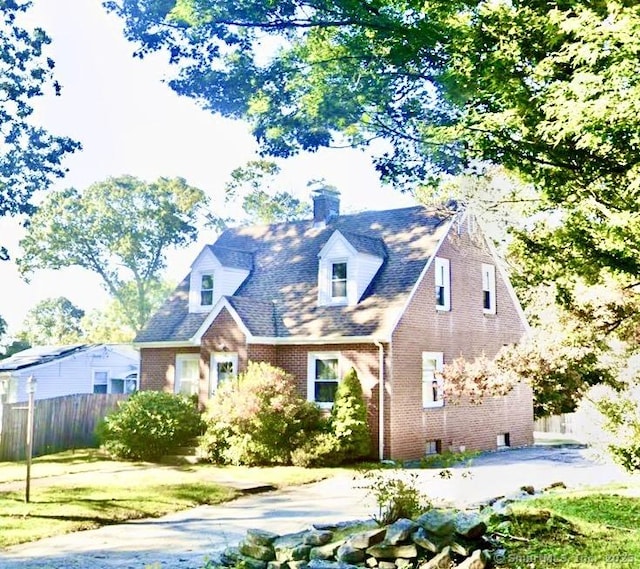 view of front facade featuring brick siding and fence