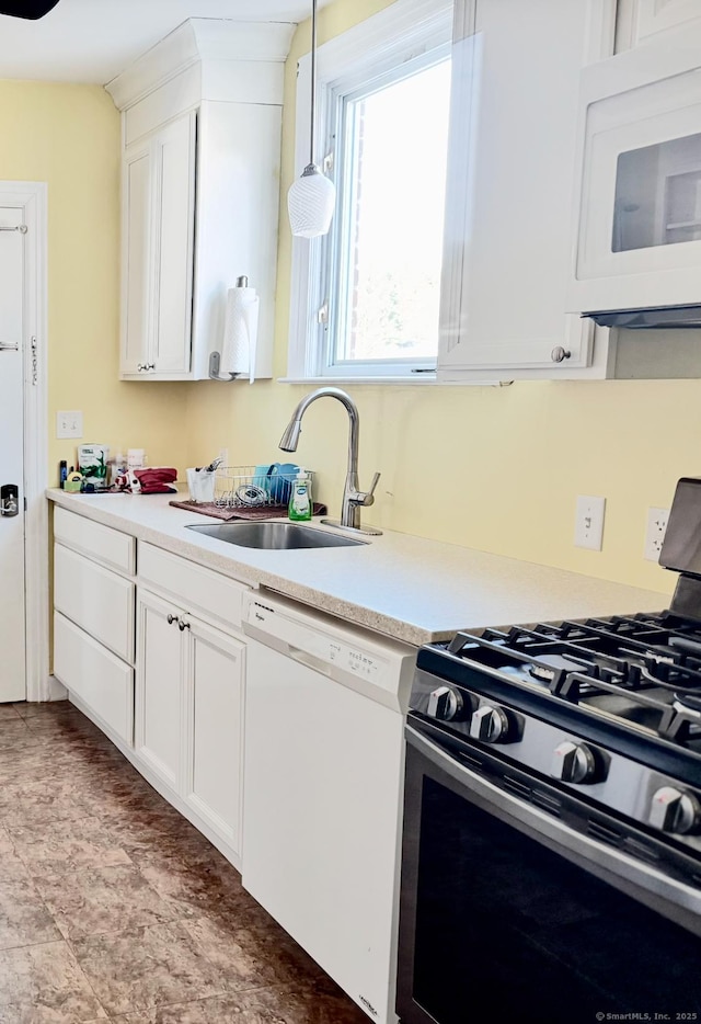 kitchen with white appliances, light countertops, a sink, and white cabinetry