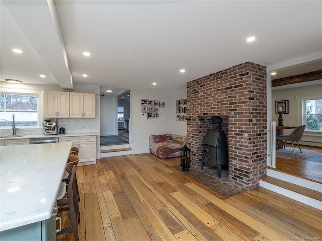 interior space featuring light wood-type flooring, a wood stove, baseboards, and recessed lighting