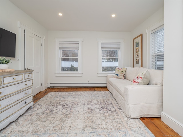 sitting room with a baseboard heating unit, baseboards, wood finished floors, and recessed lighting