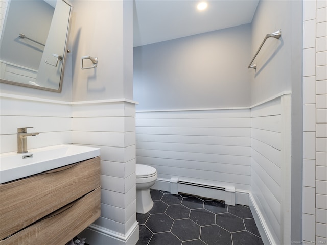 bathroom featuring toilet, a baseboard heating unit, wainscoting, vanity, and tile patterned floors