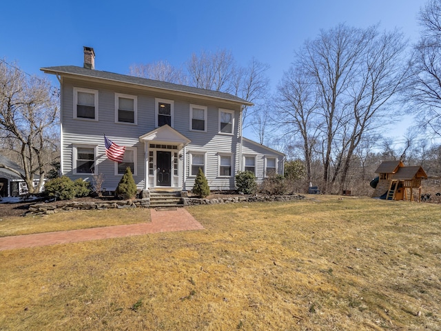 colonial inspired home featuring a chimney, a front lawn, and a playground