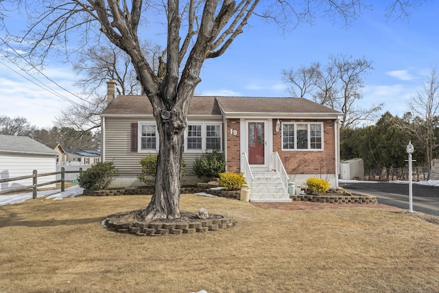 view of front of home with entry steps, brick siding, fence, a front lawn, and a chimney