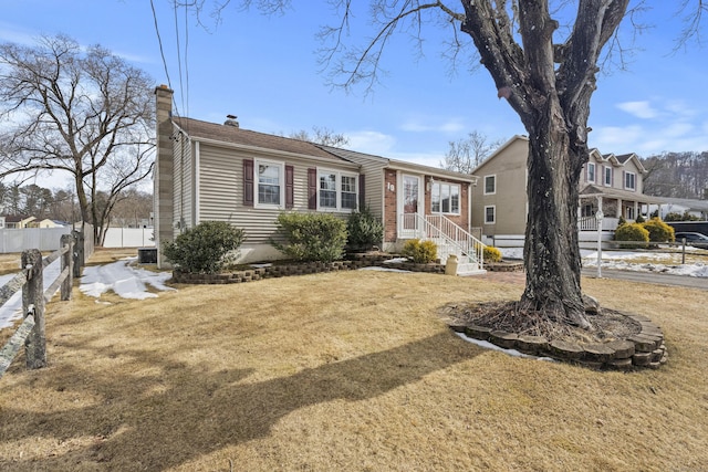 view of front of house featuring fence, a chimney, a front lawn, and central AC unit