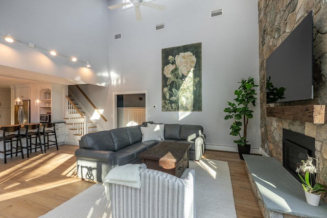 living area featuring light wood-type flooring, stairway, and visible vents