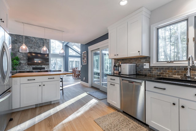 kitchen featuring a sink, white cabinetry, light wood-style floors, appliances with stainless steel finishes, and tasteful backsplash