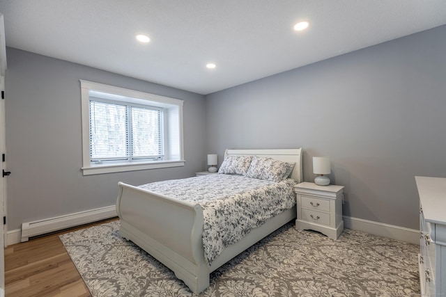 bedroom with a baseboard heating unit, light wood-type flooring, baseboards, and recessed lighting