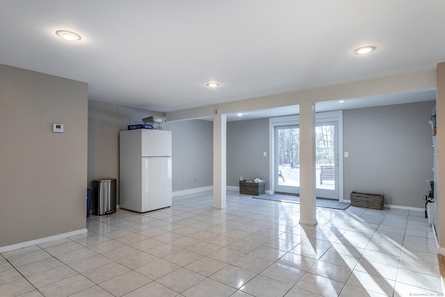 below grade area featuring freestanding refrigerator, light tile patterned flooring, baseboards, and recessed lighting