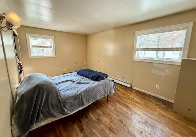 bedroom featuring baseboards, baseboard heating, and wood finished floors