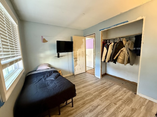 bedroom with a closet, baseboards, and wood finished floors