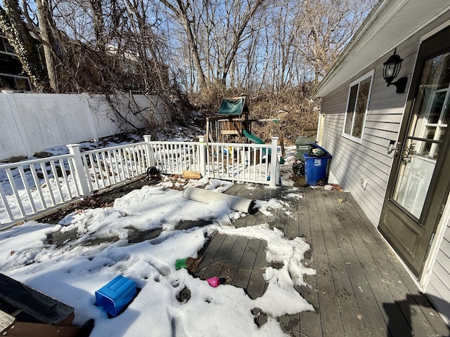 snow covered deck with a playground and fence