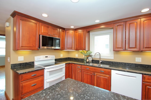 kitchen with white appliances, dark stone countertops, recessed lighting, and a sink